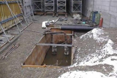 Baugrube mit Grundwasser mit Brettern verschalt