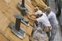 Bauarbeiter bei der Anbringung von Dämm-Material auf einem Dach
